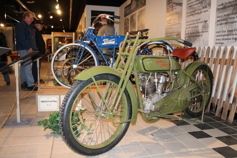A pristine 1917 Harley-Davidson Model T sits aside a 1916 Miami Power Bicycle