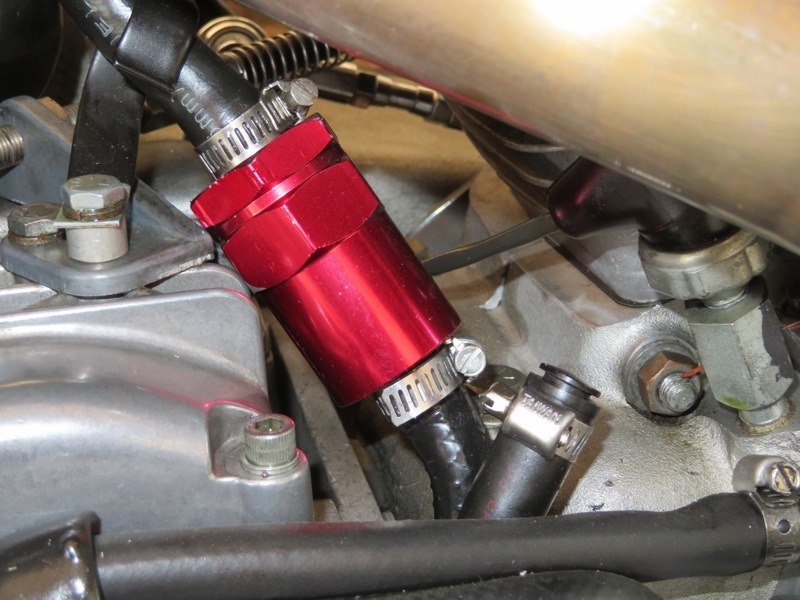 Using the hose that ran to the air cleaner (or atmosphere) install a large “air-oil” separator/ “burp valve” such as this red canister. You can be creative, but the point is to prevent any oil from start-up (especially sumped bikes) getting to the one-way “exhaust" valve that’s going to be installed “upstream.” (Theoretically, that valve should be close to the crankcases to be most effective, but considering what oil contamination might do to the valve function… a burp/separator is common sense “insurance.”)